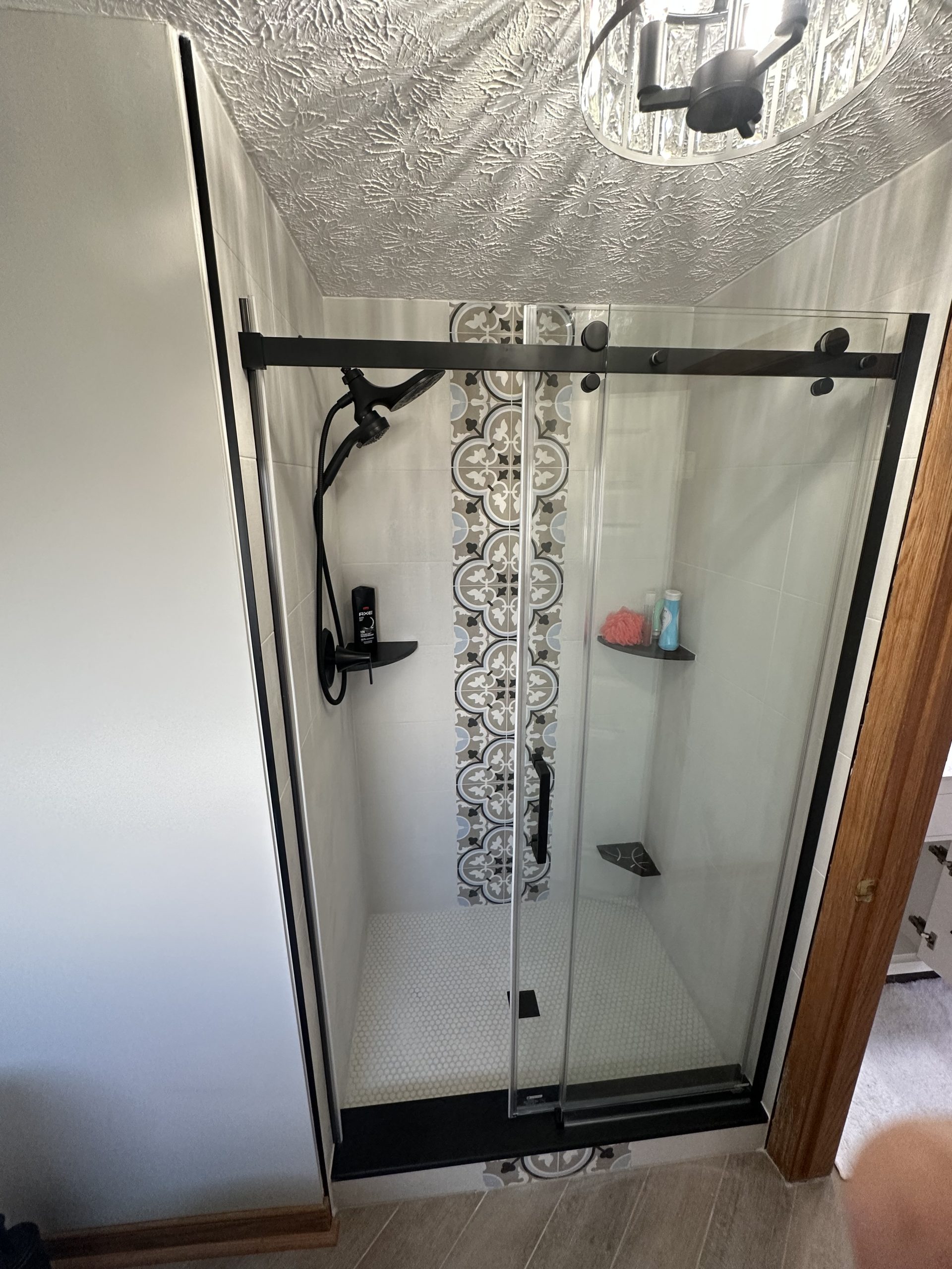 Walk-in shower with patterned tile floor and glass enclosure in Stark County, Ohio
