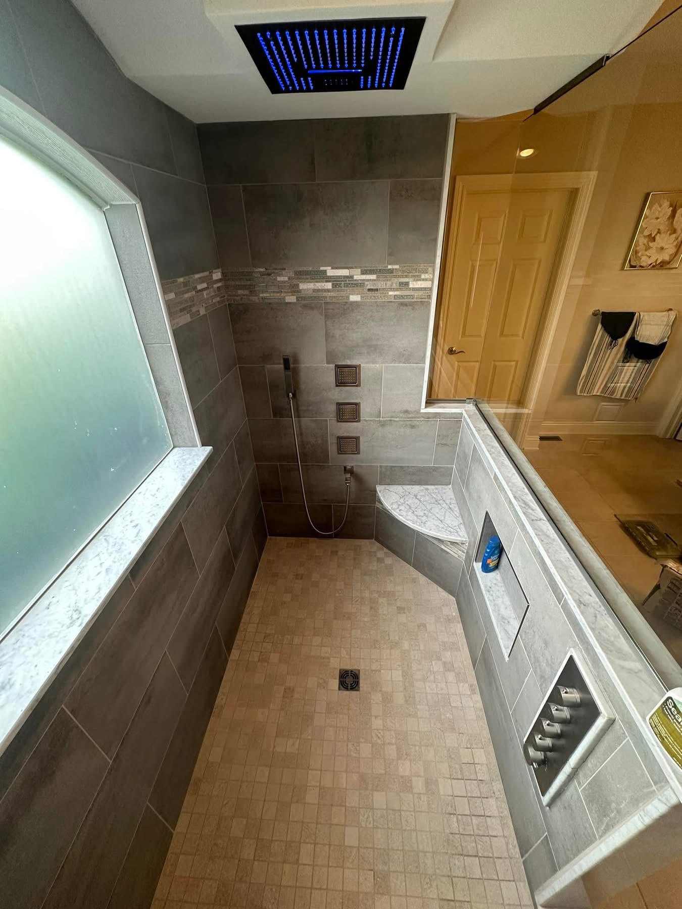 A finished walk-in shower with rainfall and wall jets — premium features that shift the appraisal but only when sized to the home.