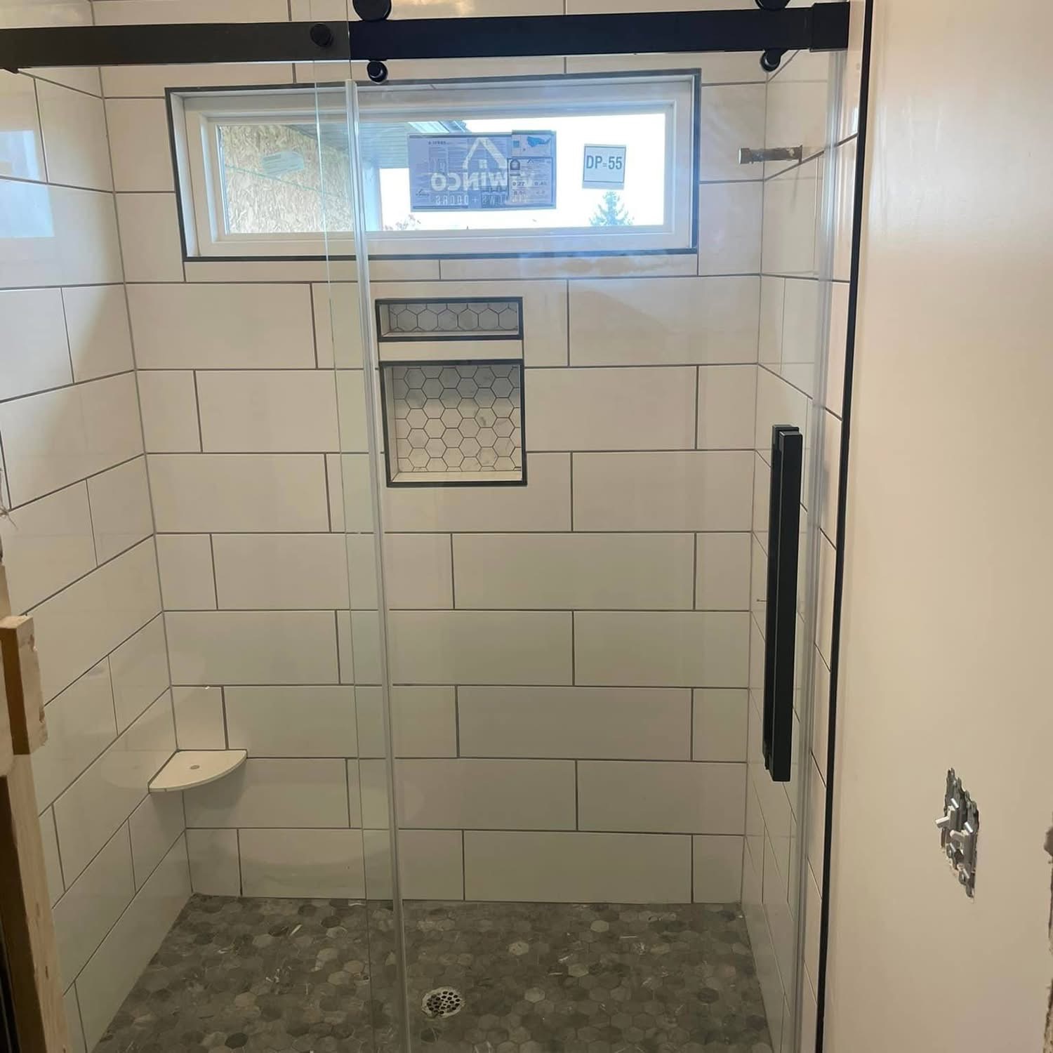 Large-format tile shower with hex tile floor by Stark Elite Home Solutions